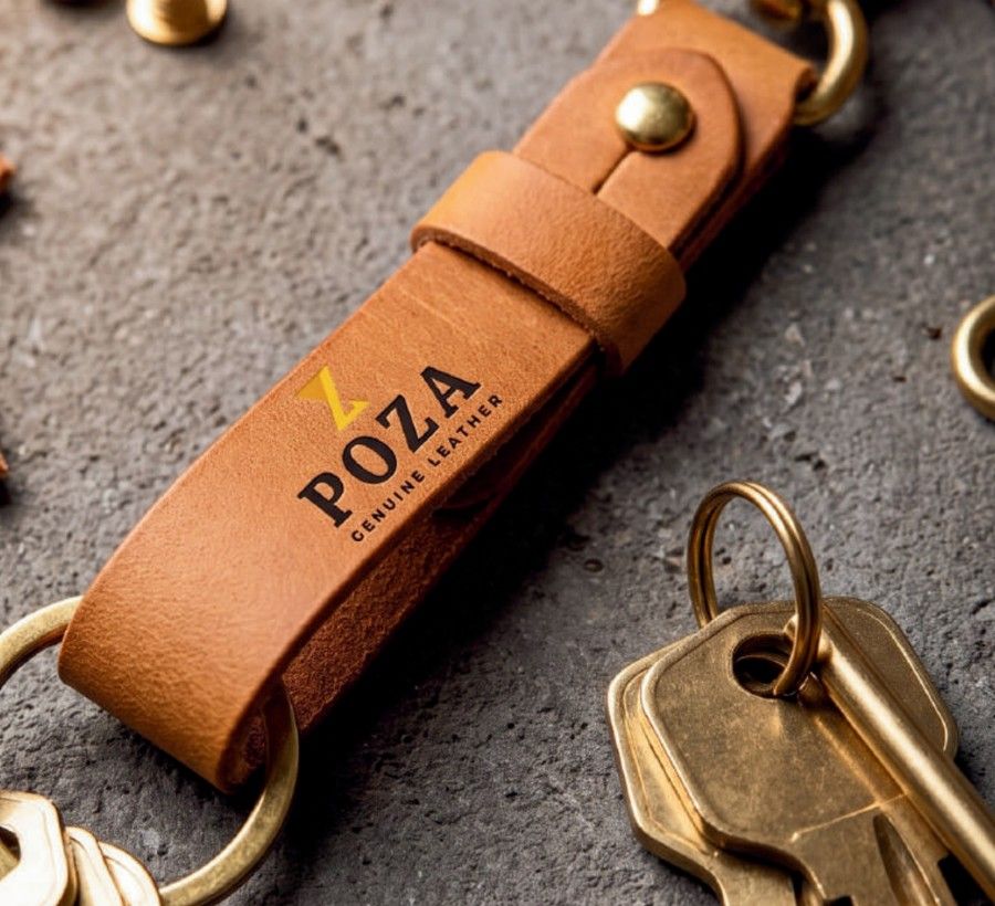Gold foil POZA logo on a tan leather key chain