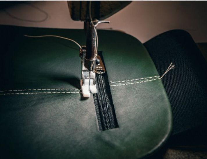 Sewing machine stitching a green leather panel